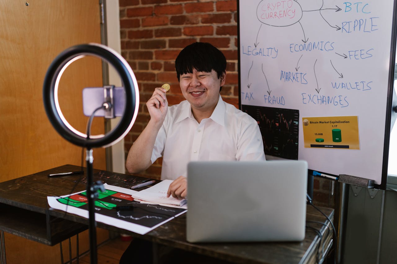 Man discussing cryptocurrency concepts online with a laptop, ring light, and whiteboard.